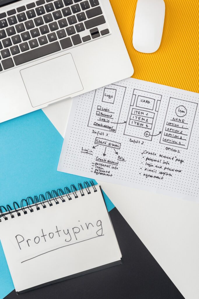 top view of notebook with prototyping lettering, laptop, computer mouse and website design template